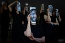 Relatives and supporters of Israeli hostages held by Hamas in Gaza hold photos of their loved ones during a performance calling for their return in Tel Aviv (AP)