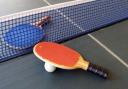 Two table tennis bats and a ball on a table.