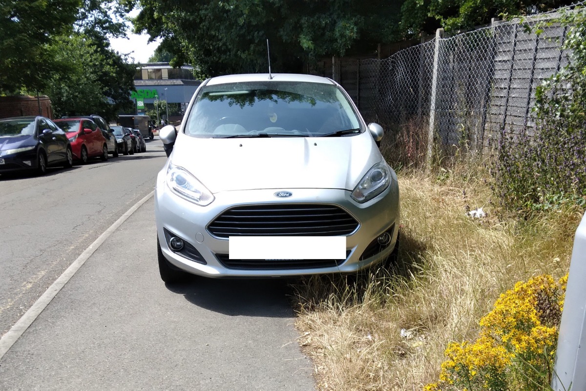 Cars parked on the pavement on Honey End Lane near Meadway Precinct