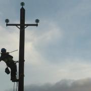 A man fixing an overhead powerline. Credit: PA