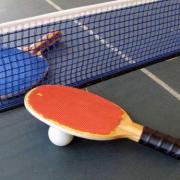 Two table tennis bats and a ball on a table.